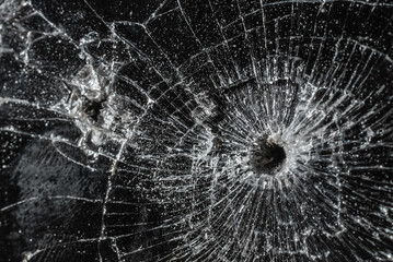 Bullet hole in a glass on the black background.closeup.