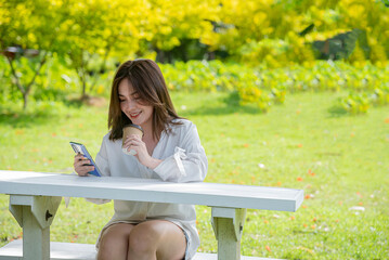 Naklejka premium beautiful asian woman look at mobile look social media or buy shopping online or pay bill by app internet banking and holding coffee cup