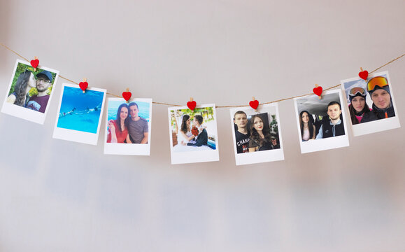 Lots of photos of a couple in love hanging on a rope on the wall with clothespins of hearts. Instant Polaroid photos.