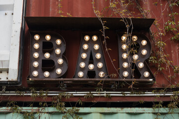 The word BAR made up of Edison light bulbs. Vintage sign made with metal letters with lamps. Bar, cafe or restaurant electric sign in retro style