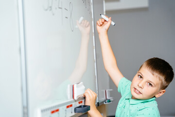 Cute child schoolboy solving math problems writing at chalk board at class. Education for primary concept.