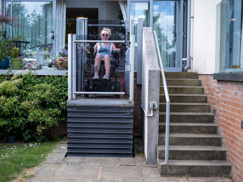 Woman in electric wheelchair using outdoor lift