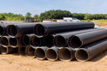 In order to build a drain system on construction site, PVC new black plastic pipes are stacked in rows for new home