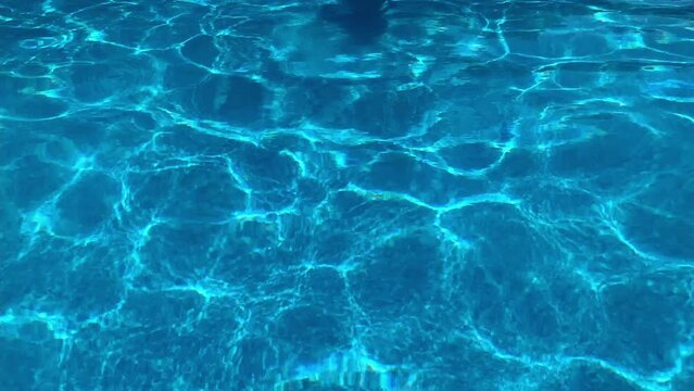 Female shadow reflection on the bottom of spa swimming pool moving hands. Vacation, resort