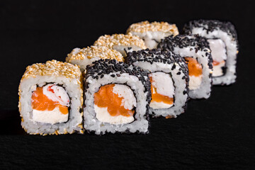 Roll with sesame seeds, rice, nori, cream cheese, salmon