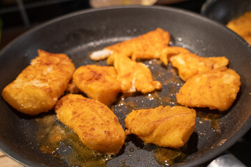 Fish filets being fried in a pan , golden brown colors 