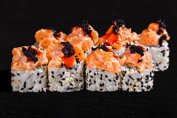 Roll with black tobiko caviar, salmon in sauce, rice and sesame seeds