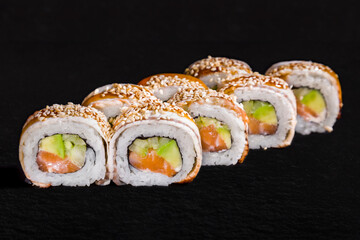 Roll with sesame seeds, eel, rice, nori, avocado, salmon