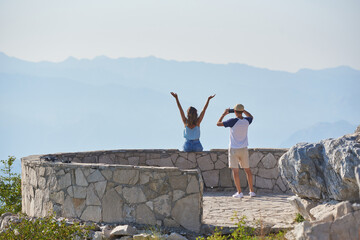 Young tourists, a couple, are photographed at a viewpoint in the mountains