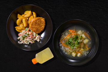 A plate of soup and a plate of potatoes, chicken cutlet