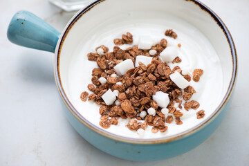 Turquoise serving bowl with greek yogurt and chocolate granola, middle close-up, selective focus