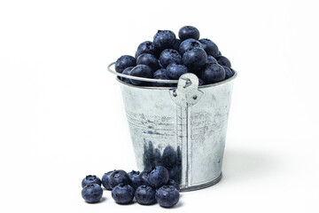 Blueberries on a white background. Small steel bucket full of blueberries. Useful and tasty berry.