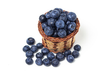 Blueberries on a white background. A small wicker basket full of blueberries. Useful and tasty berry.