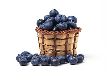 Blueberries on a white background. A small wicker basket full of blueberries. Useful and tasty berry.