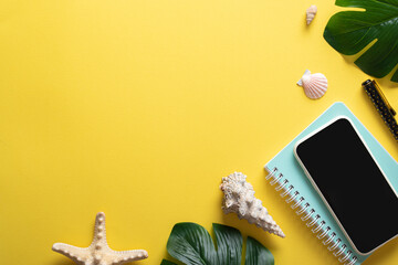 A smartphone, glasses, a blank notebook and Monstera Deliciosa leaves and shells on a yellow background. Blogging in the summer at the workplace is a business