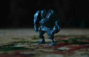 A figurine of an aggressive and vicious bald warrior in armor with a skull stands on a woolen...