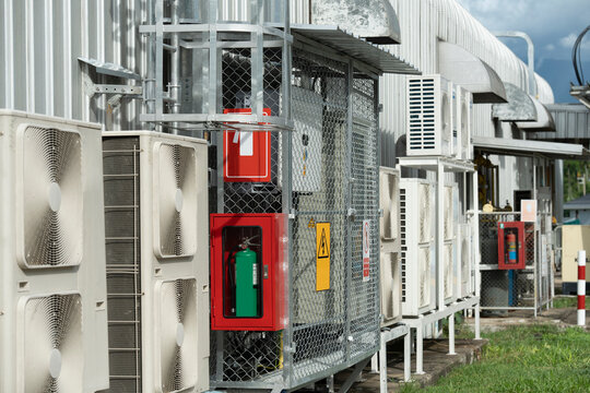 Condenser unit or compressor and control cabinets, fire extinguishers, safety systems industrial factory building roof with building wall background unit of central air conditioning or ventilation .