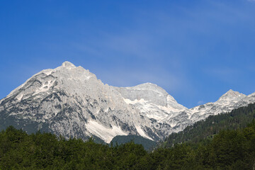 stunning high grey mountain with snow fields on a sunny day and blue sky, alpine area