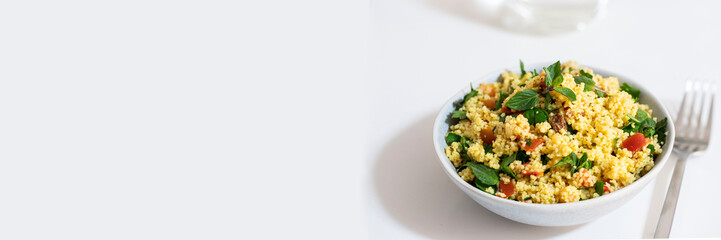 Healthy salad  with bulgur, chopped parsley, tomatoes, mint, onion and seasoned with olive oil and lemon juice on white background. Banner