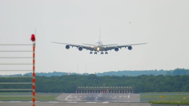 Front view of a four-engine double-deck wide-body aircraft approaching landing, slow motion. Cinematic footage of a huge unrecognizable airliner flying. Airplane silhouette arriving at the airport