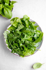 Plate with fresh arugula plants on white background.