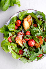 Plate with fresh salad of arugula, plants, cheese, basil and strawberry.