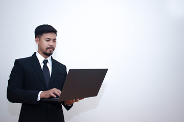 A young businessman in a shirt presses on the keyboard on his laptop with a serious expression. dissatisfied with the current state of finance, work, Isolated on gray background. Empty space for text.