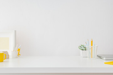 Clean desk. The minimalist home office. Table with white and yellow supplies. Creative workspace