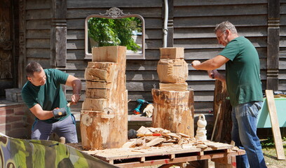 Bryansk, Russia - July 2022: wood carvers are working on making wooden sculptures with a hammer and...