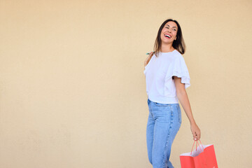 happy young woman enjoying a day of shopping with a bag in one hand and sunglasses in the other.