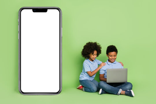 Portrait of attractive cheery pre-teen friends friendship copy space using laptop mobile app media isolated on green color background