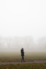 Woman walking in a London park on a foggy morning