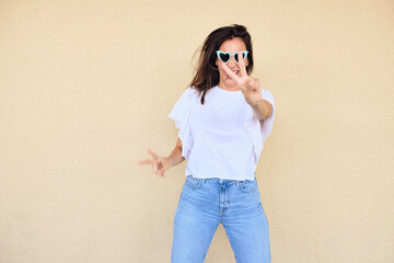 happy young woman posing in a fun way with heart shaped sunglasses 