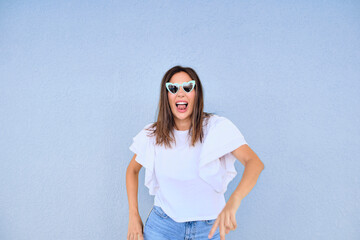 happy young woman posing in a fun way with heart shaped sunglasses 