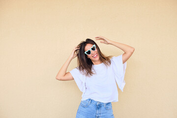 happy young woman posing in a fun way with heart shaped sunglasses 