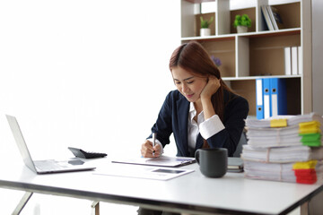 Attractive Asian businesswoman in office working on financial documents.