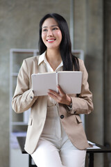 Fototapeta premium Portrait of a charming business woman in the office standing holding a notepad and pen.