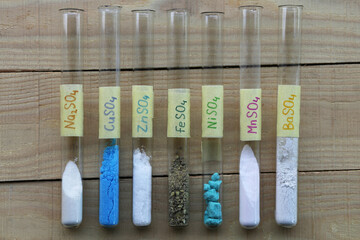 Colored sulfate salts of various metals in test tubes: sodium white anhydrous, copper blue, zinc white, iron dark green, nickel light green, manganese pale pink, barium white.