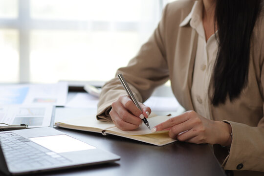 Close-up woman writing notes on notepad.