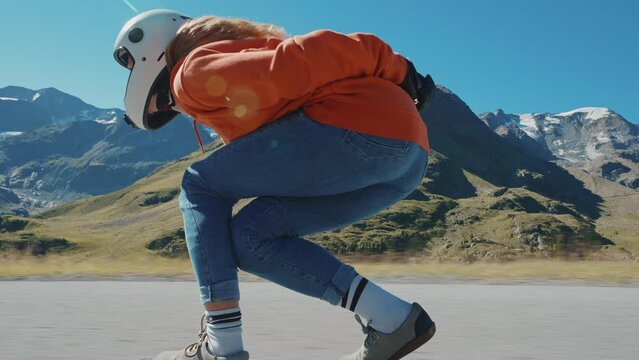 Cinematic downhill longboard session. Young woman skateboarding and making tricks between the curves on a mountain pass. Concept about extreme sports and people