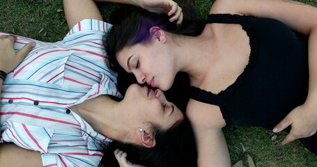 Millennial lesbian girls lying on grass kissing and dating. Caring loving LGBT relationship