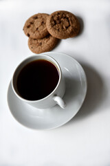 Tea pair and oatmeal cookies with chocolate on a white background. Delicious lunch with tea and sweet cookies. Porcelain tea set with a hot drink.
