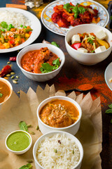 chicken tikka masala, kadai chicken; coconut sabdji, indias samosa, veg curry;bainkar bharta,  Indian food on dark blue stone background with spices vertical