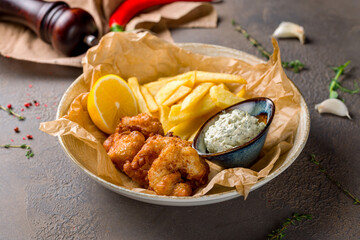 fish and chips with french fries and tartar sauce on brown table