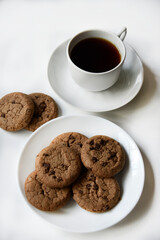Tea pair and oatmeal cookies with chocolate on a white background. Delicious lunch with tea and sweet cookies. Porcelain tea set with a hot drink.