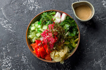 Ahi poke with tuna, avocado,cucumbers,tomatoes,chukka,sesame and nori top view on grey table