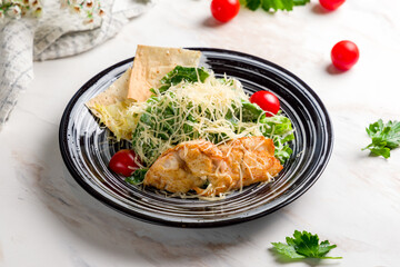 Salad caesar with chicken on black plate on white marble table