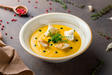Soup cream of pumpkin with croutons on brown table