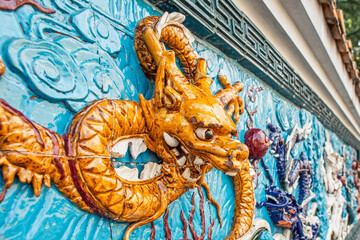 Fototapeta premium Ceramic wall decor in the form of a yellow Chinese dragon head