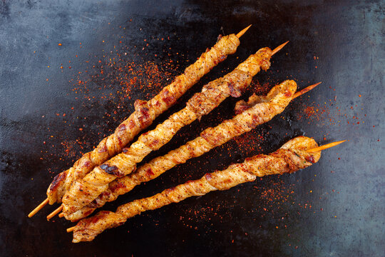Traditionelle gegrillte Fackeln mit Speck und scharfer Marinade um einen Holzspie&szlig; gewickelt serviert als Draufsicht auf einem rustikalen Board mit Textfreiraum  